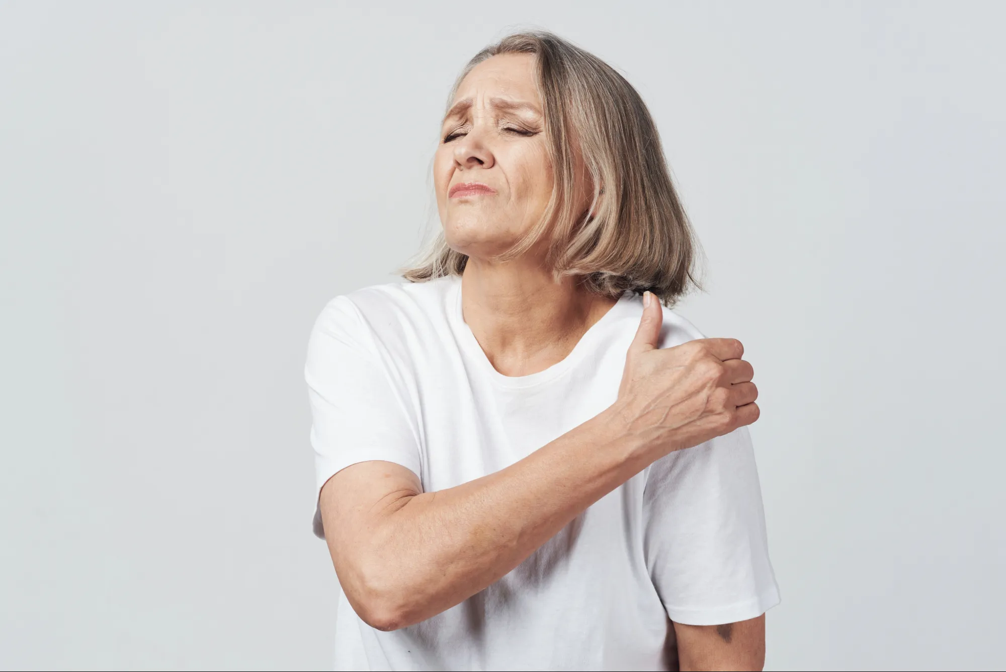 Woman holding her aching shoulder, a common sign of shoulder pain without injury